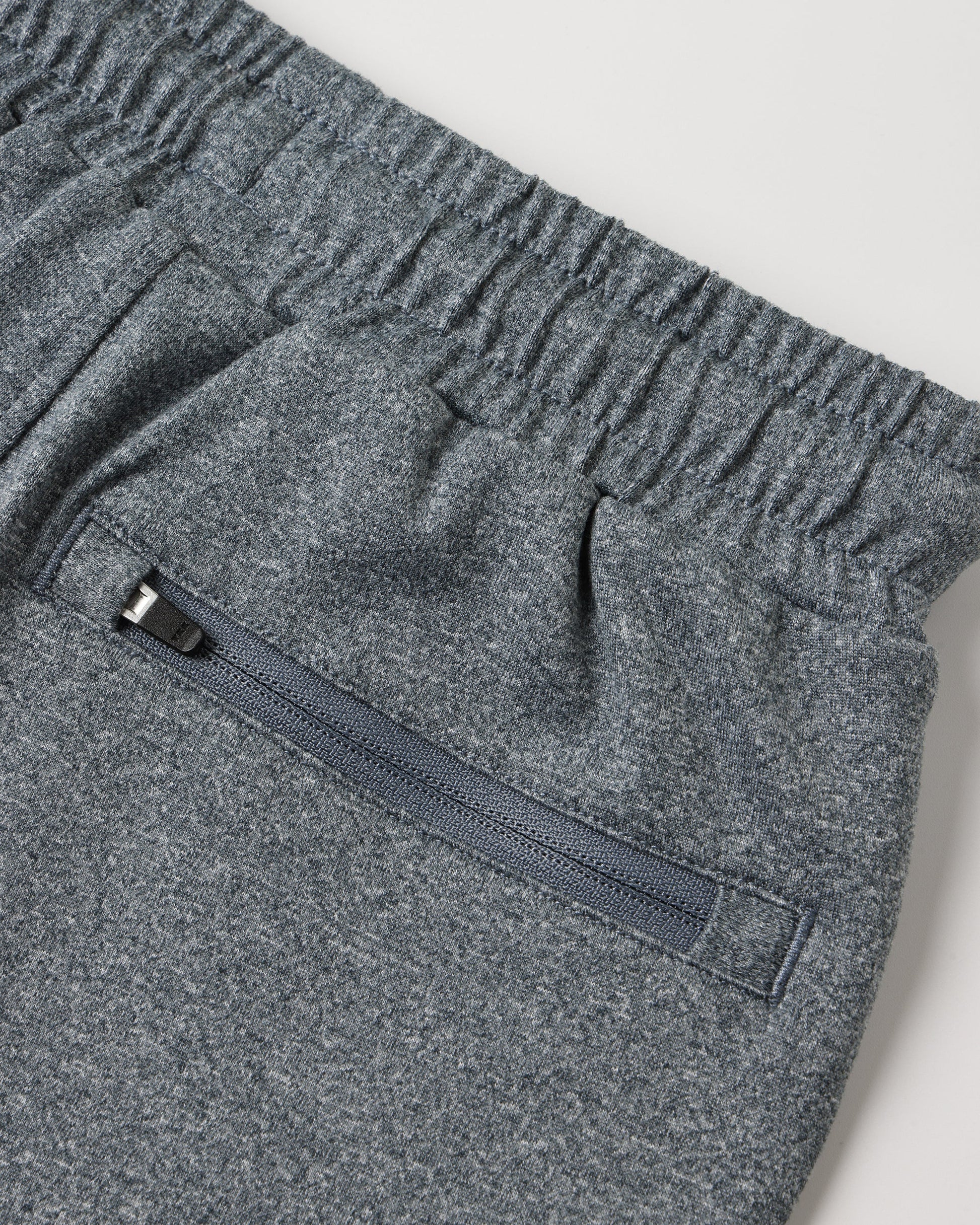 Close-up of the Boys’ Oceanside Tech Short by Rylee & Cru in gray, featuring an elastic waistband and a zip back pocket with a black pull tab, photographed on a light background to highlight these comfortable and convenient everyday essential shorts.