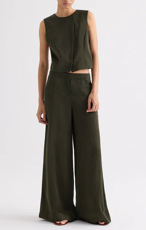 Person wearing TWP’s Rosen Green sleeveless top with the Demie Coated Viscose Linen Pant, standing against a plain light background.