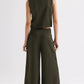 A person faces away from the camera, wearing a sleeveless dark top and matching TWP Demie Coated Viscose Linen Pant with a wide-leg silhouette.