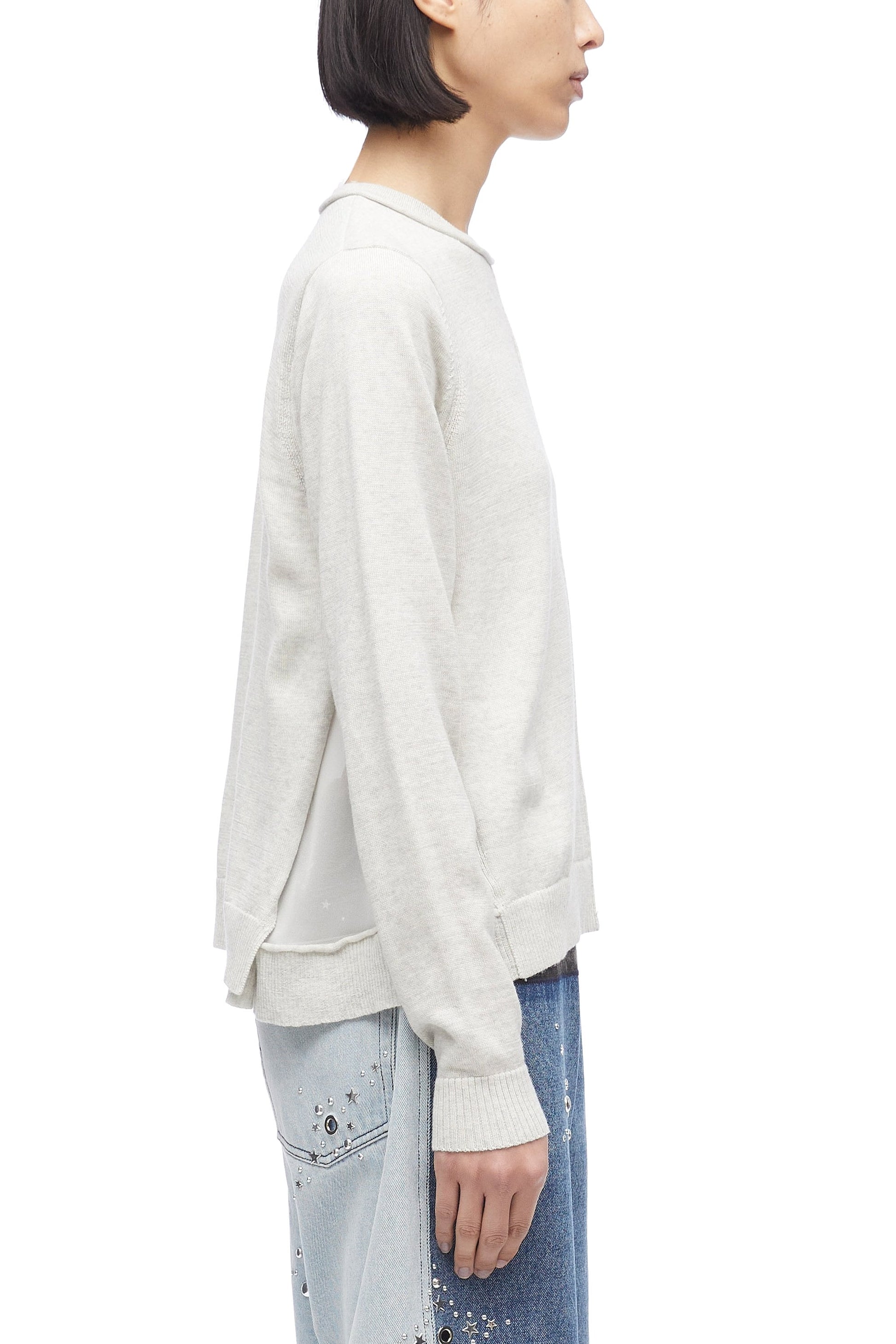 Side profile of a person wearing a 3.1 Phillip Lim Merino Knit Top pullover and embellished jeans.