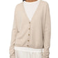 A person is elegantly dressed in the Lisa Yang Lisa Yand Abby Cashmere Cardigan in beige, layered gracefully over a crisp white shirt.