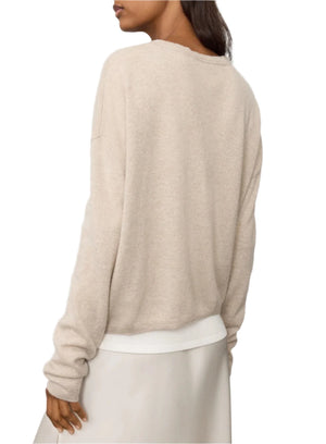 A person is pictured from the back wearing the Lisa Yang Abby Cashmere Cardigan in a featherweight, loose-fitted silhouette, paired with a light gray skirt creating an essential trans-seasonal look.