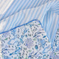 Close-up of Timo & Violet Crib Quilt bedsheets—one in blue and white stripes, the other featuring ocean-themed illustrations with octopuses, fish, and coral.