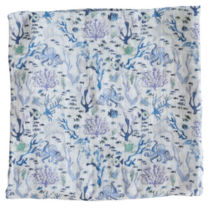 The Timo & Violet Shawl Blanket is a square cloth with a blue and purple underwater coral reef pattern, featuring fish, seaweed, octopuses, and marine motifs on a light background—ideal as a baby accessory.