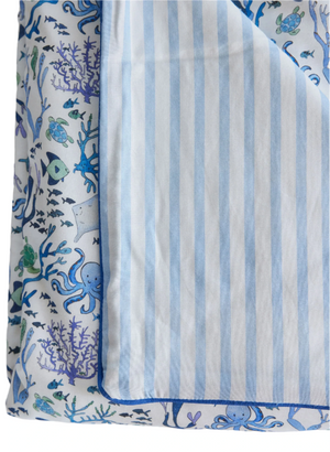 The Timo & Violet Crib Quilt is a silky soft, reversible quilt with ocean-themed sea creatures on one side and light blue and white stripes on the other, adding charming style to any crib.
