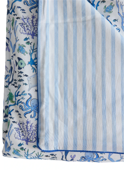 The Timo & Violet Crib Quilt is a silky soft, reversible quilt with ocean-themed sea creatures on one side and light blue and white stripes on the other, adding charming style to any crib.