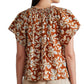 A person is wearing an Apiece Apart Patricia Flutter Sleeve Top made from hand-printed fabric with a gathered neckline and short sleeves. The photograph, taken from the back, showcases the upper half of their torso.