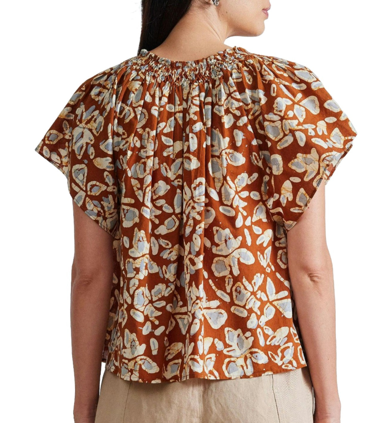 A person is wearing an Apiece Apart Patricia Flutter Sleeve Top made from hand-printed fabric with a gathered neckline and short sleeves. The photograph, taken from the back, showcases the upper half of their torso.