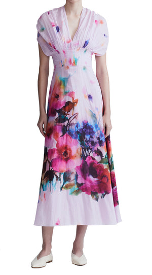 Person wearing a Lela Rose Watercolor Floral Cotton Voile Isabel Dress by Lela Rose made from airy cotton voile with short sleeves and a deep V-neck, paired with white shoes. The dress features a whimsical watercolor floral print.