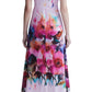 A person is standing facing away, wearing the Lela Rose Watercolor Floral Cotton Voile Isabel Dress, a white cotton voile ensemble adorned with a watercolor floral print towards the bottom half. They are also wearing white flat shoes.