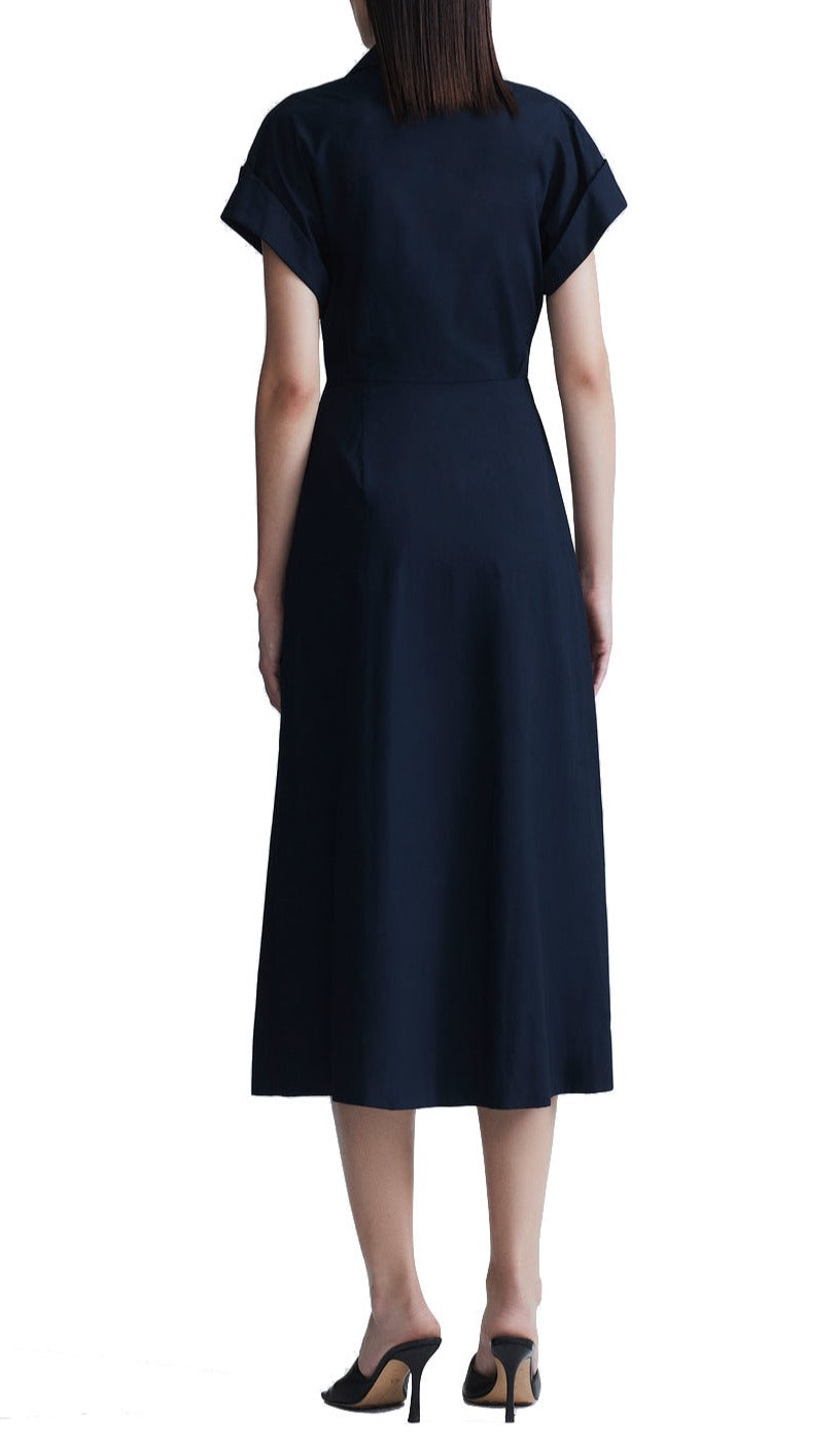 Woman standing with her back facing the camera, wearing a navy blue Lela Rose Cotton Poplin Short Sleeve Button Down Midi Dress with jewel facet buttons and black high heels.