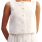 A woman wearing the POSSE Rio Top—a sleeveless white, relaxed-fit top with a square neckline and front buttons—paired with white pleated pants.