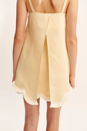 A person is photographed from behind wearing the POSSE Essie Top, a sleeveless, light yellow piece with a scalloped hem and a square neckline.