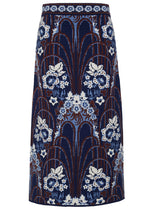 The Clara Skirt by Cara Cara is a high-waisted midi sheath featuring a blue, white, and brown floral and arch jacquard pattern on a dark background.
