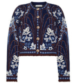 The Livi Jacket by Cara Cara is a navy blue, long-sleeved jacquard knit cardigan featuring white and brown floral and leaf patterns, finished with gold decorative buttons.
