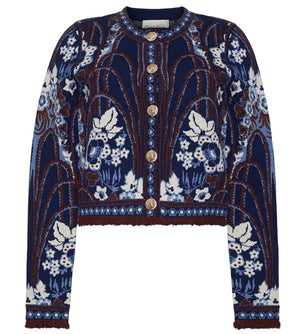 The Livi Jacket by Cara Cara is a navy blue, long-sleeved jacquard knit cardigan featuring white and brown floral and leaf patterns, finished with gold decorative buttons.