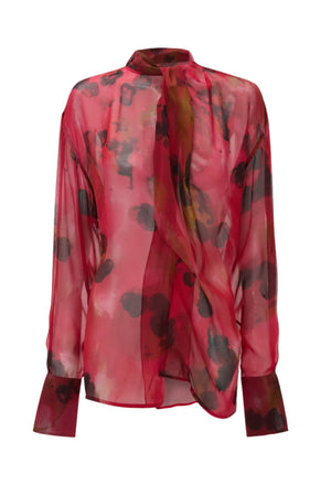 The Drape Detail Blouse by Victoria Beckham features a sheer red and black floral print, long sleeves, high neckline, draped front detail, and is crafted from 100% silk.
