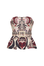 The Tilda Top by Cara Cara is a strapless peplum style with boning for structure, a belted waist with square buckle, and an ornate red, black, and cream pattern.