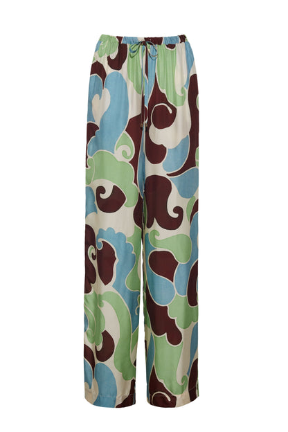 The Girona Pant by Cara Cara features a wide-leg, flowy silhouette with an elastic waistband, bold abstract pattern in green, blue, brown, and cream, and gold cord ends on the drawstring for an elegant finish.