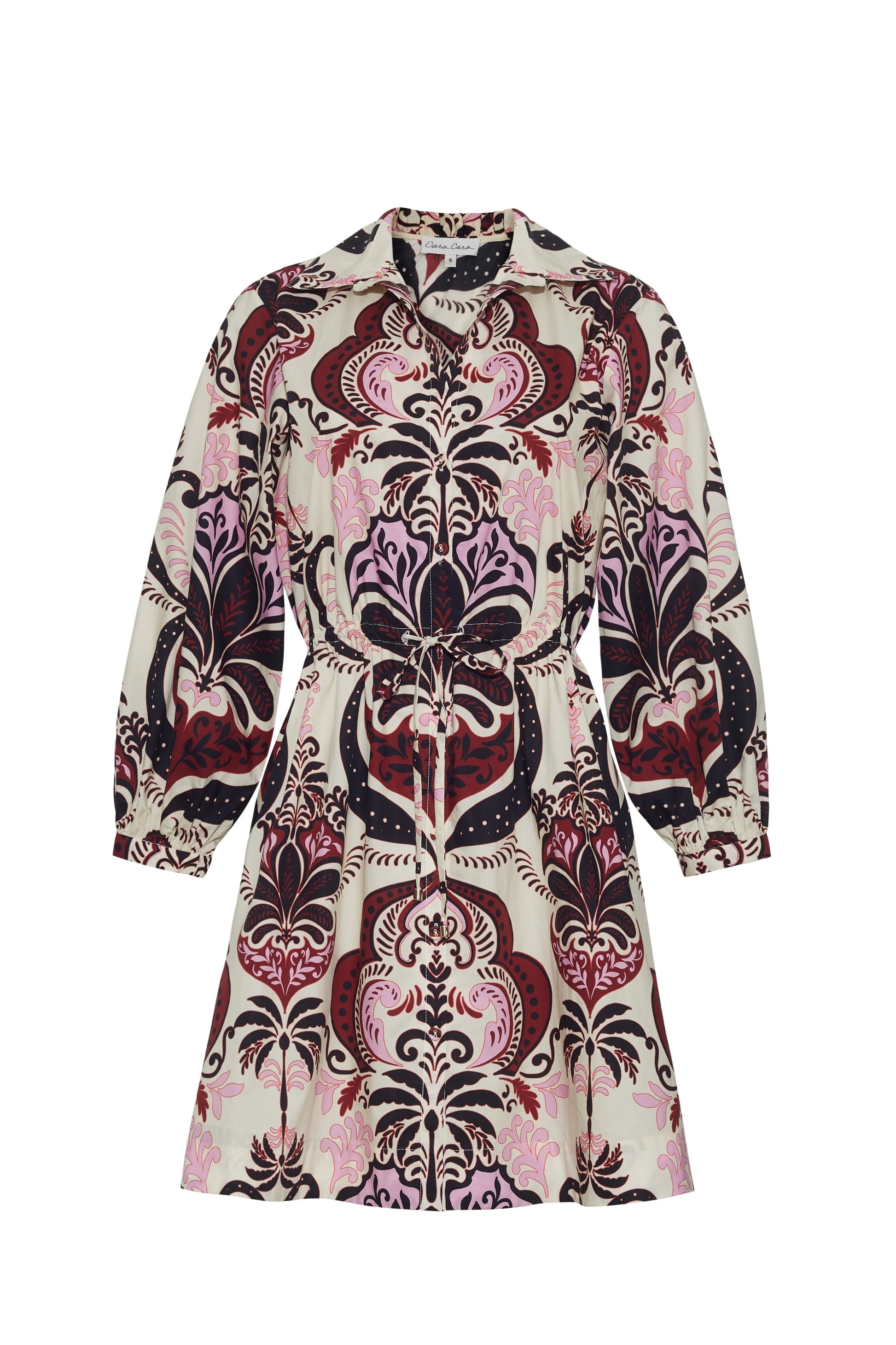 The Cara Cara Henry Dress is a long-sleeved, button-down dress with a collared neckline, featuring an ornate pink, burgundy, and black pattern on a light background.