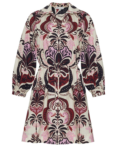The Cara Cara Henry Dress is a long-sleeved, button-down dress with a collared neckline, featuring an ornate pink, burgundy, and black pattern on a light background.