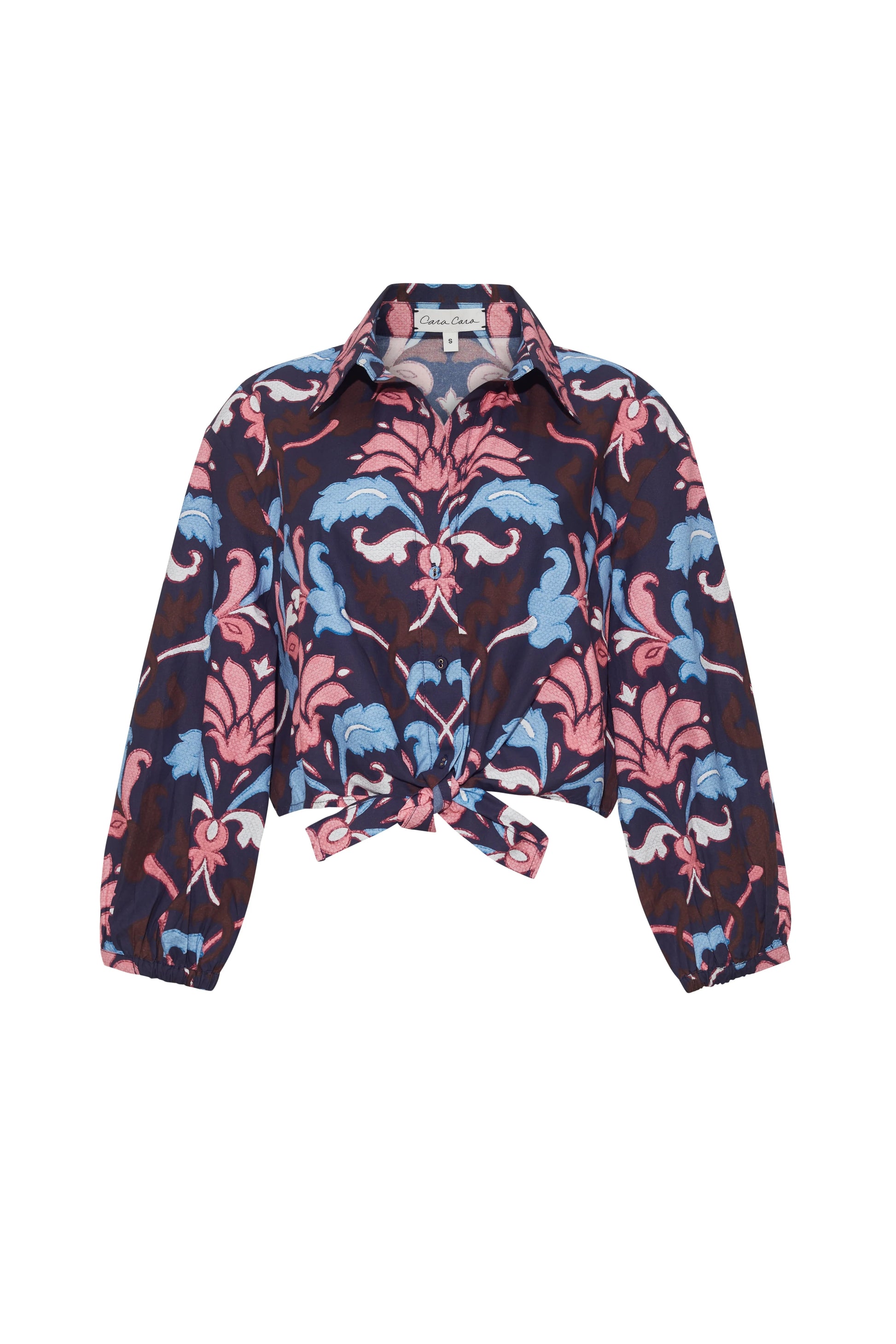 The Cara Cara Rumson Top is a printed long sleeve shirt with a pink, blue, and navy floral pattern, button-down collar, and a stylish front tie knot.