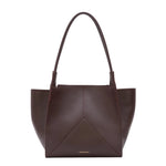 The Victoria Tote by Victoria Beckham is a dark brown Italian-crafted bag with two handles, a structured geometric design, and a luxurious suede-lined interior.