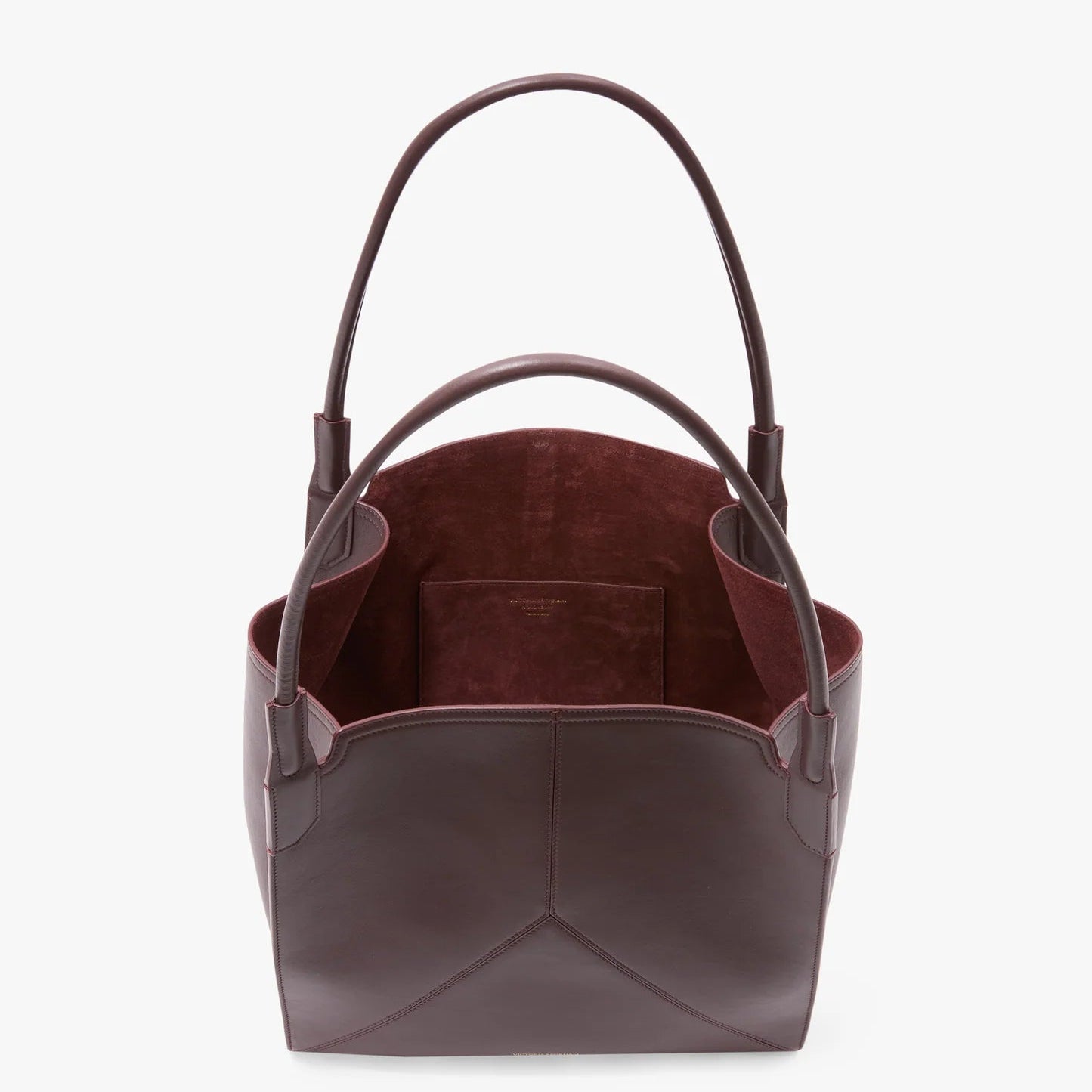 The Victoria Beckham Victoria Tote is a burgundy leather bag with two handles, an open top, and a matching interior pocket. Expertly crafted in Italy, it’s shown from above on a white background.