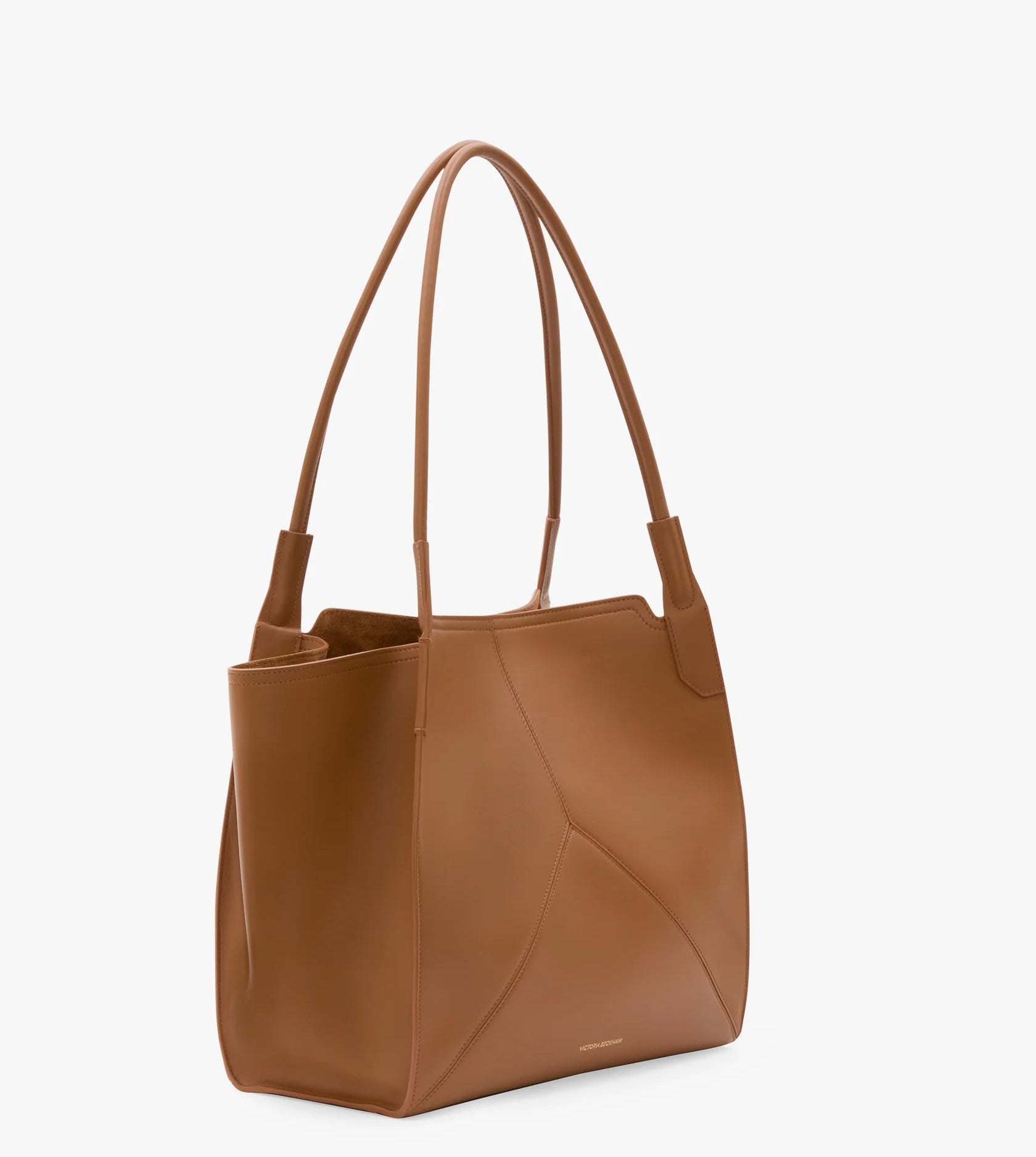 The Small Victoria Tote by Victoria Beckham features smooth brown tan calf leather, double shoulder straps, and minimal stitching, shown against a plain white background.
