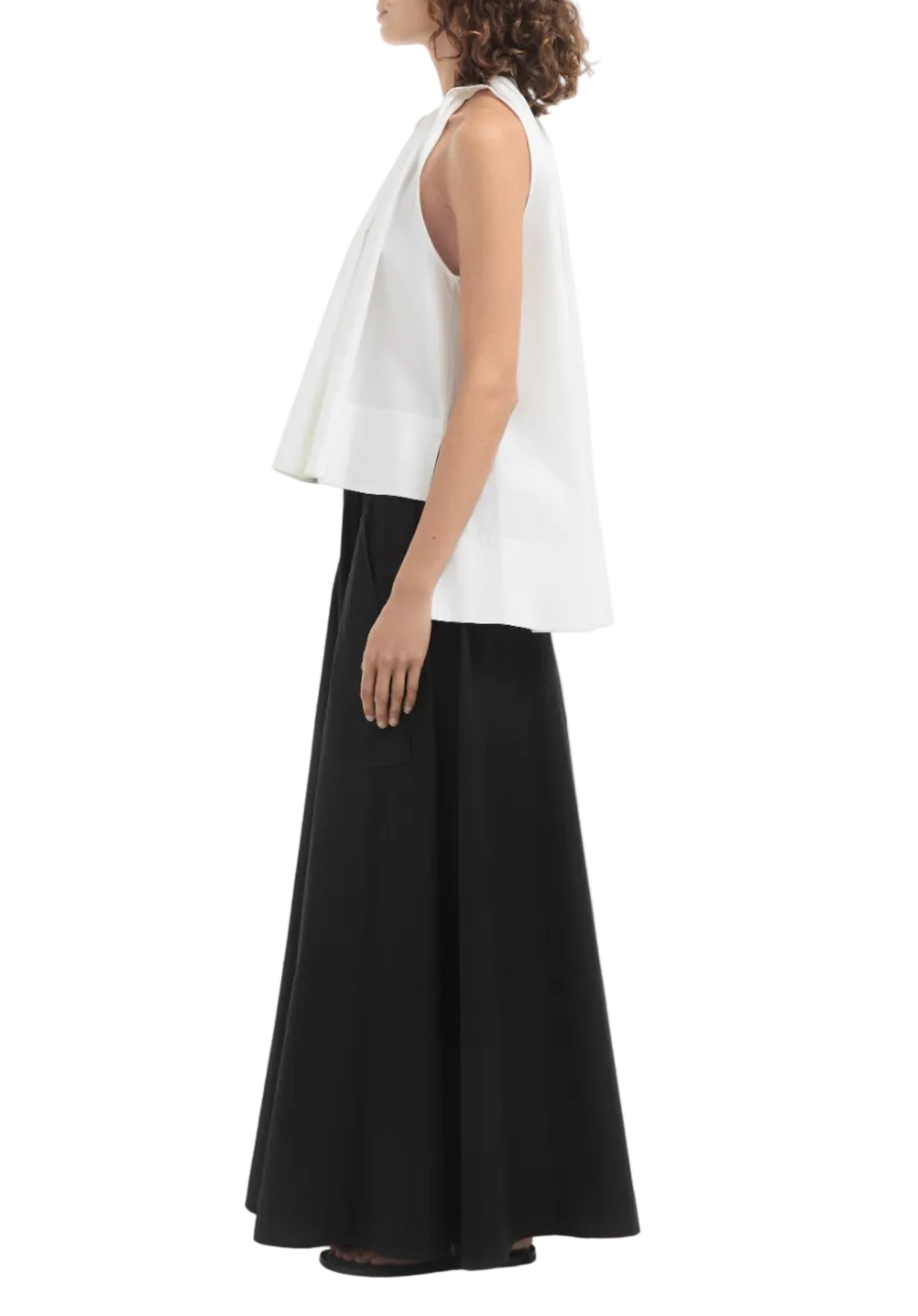 A woman stands in profile against a plain white background, wearing the CO Gathered Tunic Shirt and a long black skirt.