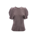 The Bela Top by Victoria Beckham is a short-sleeved, mauve blouse with puffed shoulders and a round neckline, made from grey crepe back satin and shown on a white background.