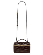The Vanity Croc Crossbody by Victoria Beckham is a dark brown, rectangular bag in croc-embossed leather with a gold zipper, top handle, adjustable strap, and organised compartments—shown against a white background.