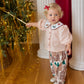 Toddler wearing a pale pink button-up top with an embroidered collar and patterned pants from the Baby Girls’ Noelle 2-Piece Set by Pink Chicken.