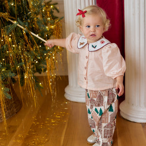 Toddler wearing a pale pink button-up top with an embroidered collar and patterned pants from the Baby Girls’ Noelle 2-Piece Set by Pink Chicken.
