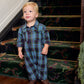 A toddler wearing a blue and green tartan Baby Boys’ Easton Jumper standing on a staircase.