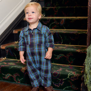 A toddler wearing a blue and green tartan Baby Boys’ Easton Jumper standing on a staircase.