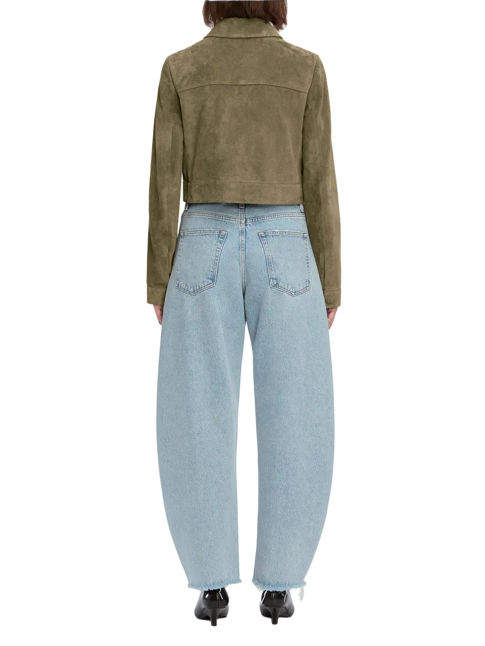 A person is seen from the back wearing The Bubble Crop by Frame, an olive green cropped jacket, with light blue high-rise barrel jeans and black shoes.