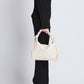 A person wearing a black outfit carries the Proenza Schouler Medium Drawstring Shoulder Bag, which features smooth leather and a twisted handle.