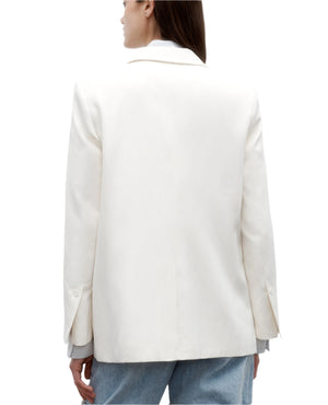 A person wearing a white TWP Tabitha Blazer and blue jeans is shown from the back against a plain white background.