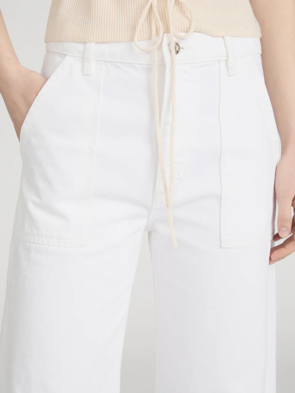A person wearing Frame’s The Bow Cargo high-rise barrel jeans with cargo pockets and a beige waist-tied top. Only the lower torso and thighs are visible, highlighting The Bow Cargo’s subtle utilitarian style.