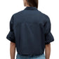 A person with long brown hair is seen from the back wearing the TWP Next Ex Shirt, a dark blue vintage-washed poplin cropped shirt with a boxy silhouette, paired with blue jeans, set against a plain white background.