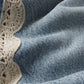 Close-up of light blue denim from Frame’s The Crochet Bow Crop, detailed with a delicate cream crochet trim along one edge.