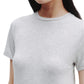 A person wearing the TWP His Tee, a plain light gray crewneck t-shirt crafted from ultra-soft cotton, is shown from shoulders to mid-torso with a neutral expression.