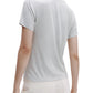 Model wears the TWP His Tee in light gray ultra-soft cotton and white pleated pants, shown from the back against a plain background.