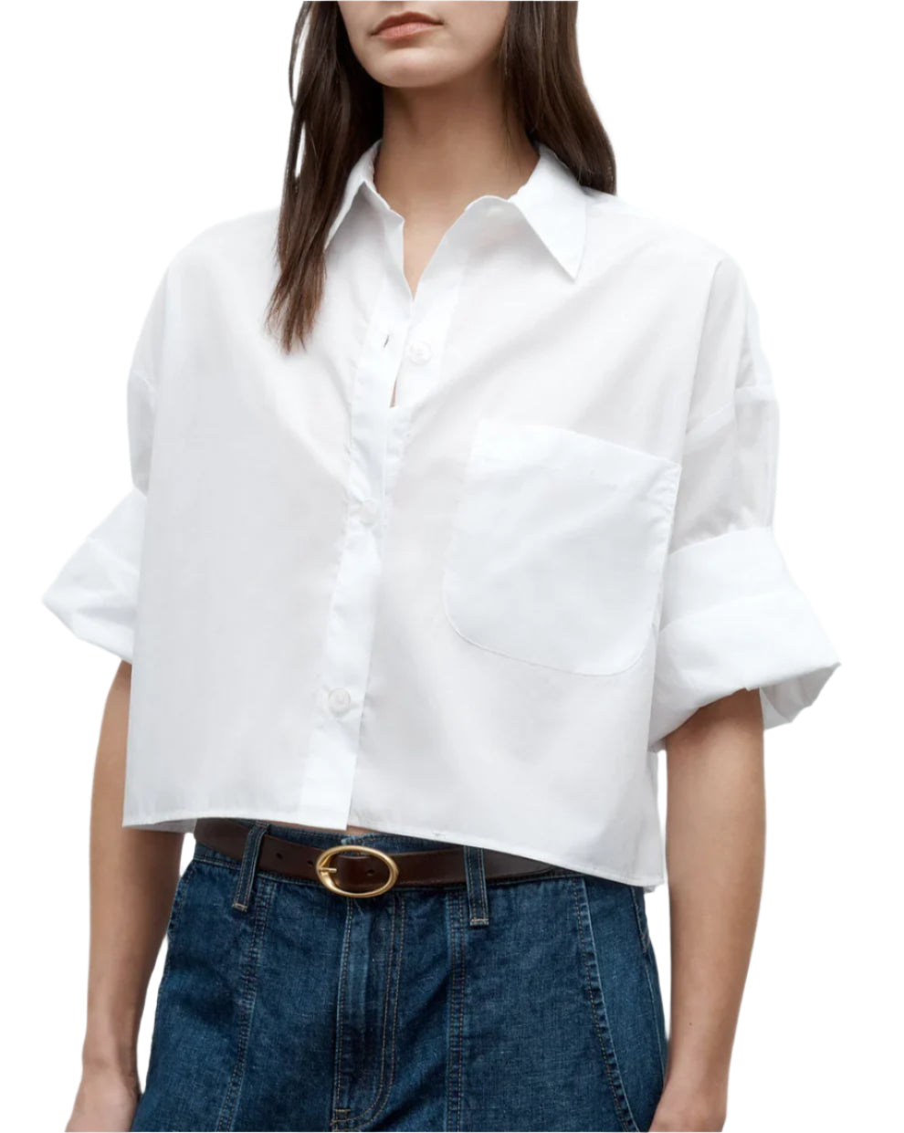 Wearing the TWP Next Ex Shirt, a vintage washed white poplin button-up with rolled sleeves, tucked into high-waisted blue jeans and styled with a brown belt.
