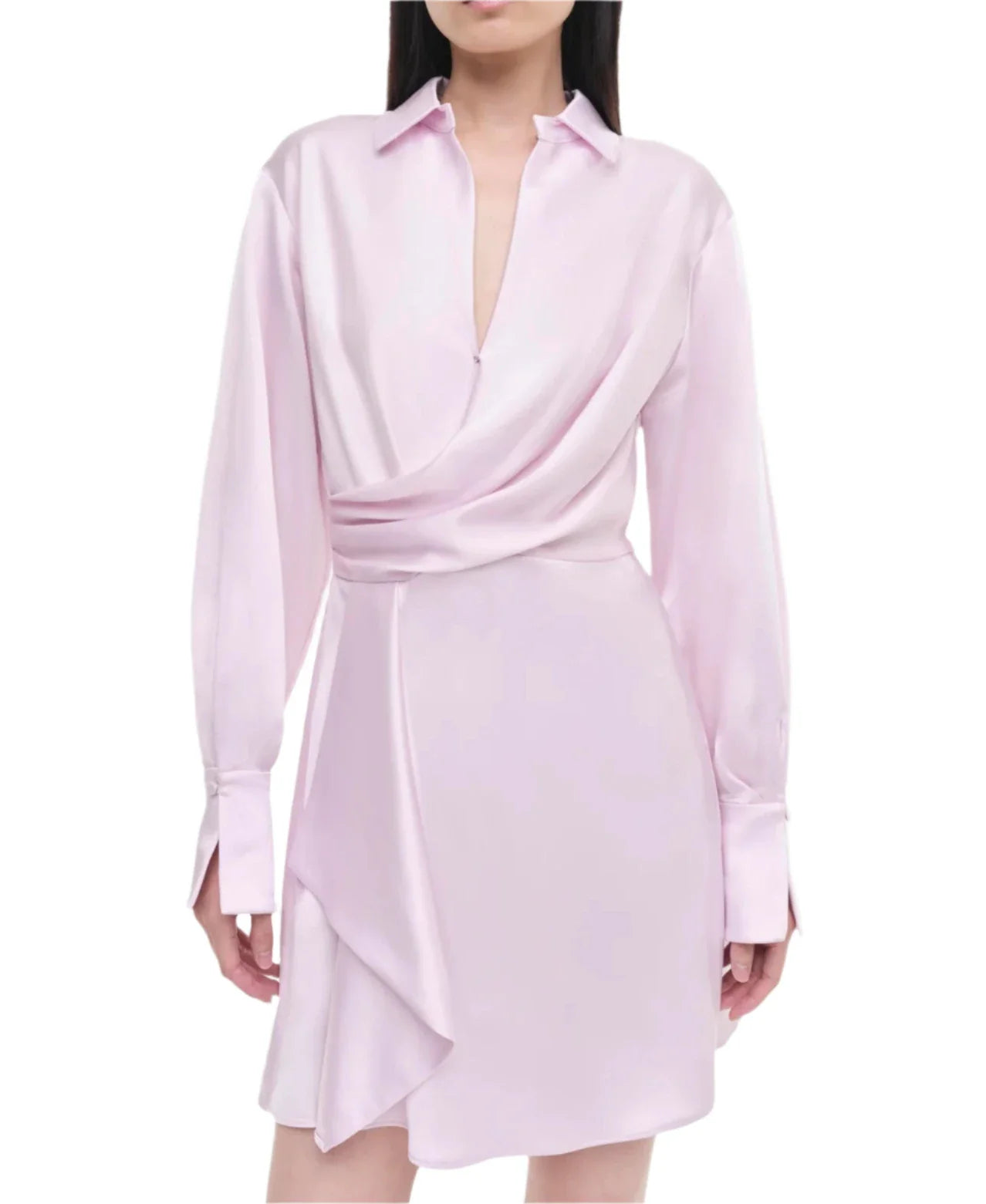 A person wearing the Simkhai Talit Draped Front Mini Dress showcases a long-sleeved, light pink satin design with an asymmetrical hem, exuding a modern silhouette.