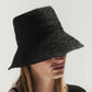 A person wearing a large black Janessa Leone Felix hat that covers their eyes, against a plain white background.