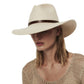 Woman with her head tilted down, wearing a wide-brimmed white UPF 35+ Janessa Leone Judith Hat and a beige textured top, isolated on a white background.