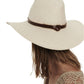 A person viewed from the side wearing a Janessa Leone Judith Hat, with a wide-brimmed, UPF 35+ white hat and a beige crocheted top, with the background omitted.