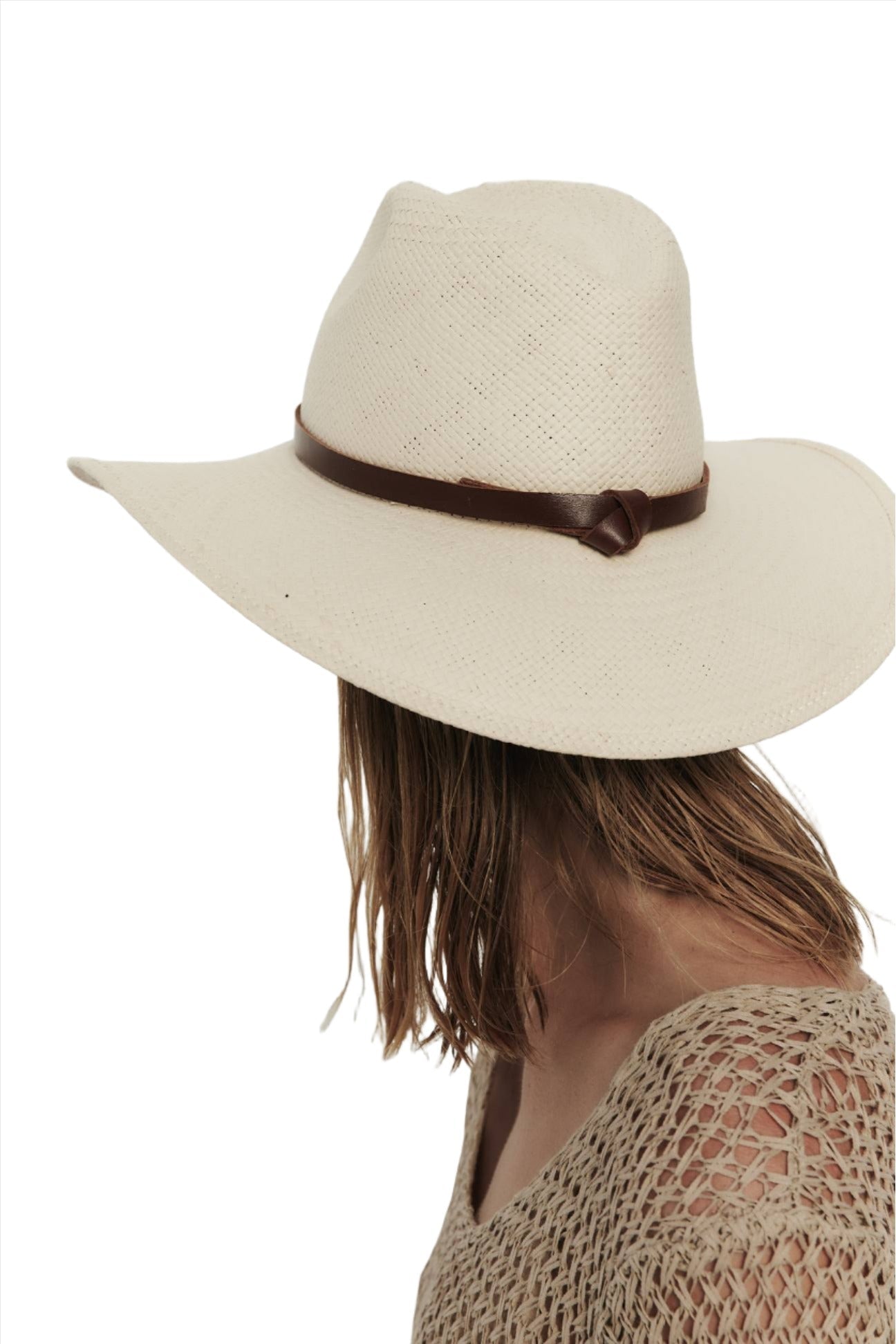 A person viewed from the side wearing a Janessa Leone Judith Hat, with a wide-brimmed, UPF 35+ white hat and a beige crocheted top, with the background omitted.